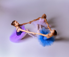 Three little ballet girls sitting in tutu and posing together