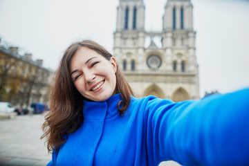 Fototapeta premium Beautiful tourist in Paris on a fall day, making selfie