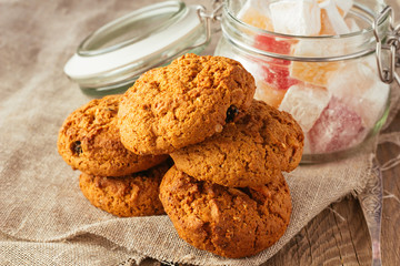 Oatmeal cookies and jar with sweeties on linen cloth
