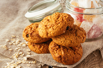 Oatmeal cookies and jar with sweeties on linen cloth