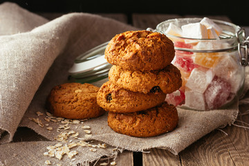 Oatmeal biscuits and jar with sweeties on linen cloth