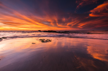 orange sunset with reflection on wet sand