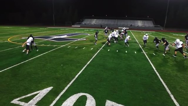 The camera pans overhead as a football player avoids being tackled and makes a touchdown
