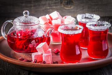 Hibiscus tea in glasses with turkish delight on rustic wooden background.