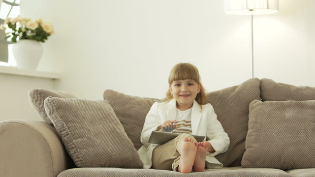 Little girl typing on tablet and smiling