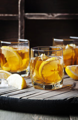 Cold whiskey with ice and lemon on the vintage table