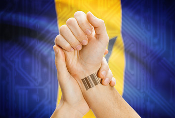Barcode ID number on wrist and national flag on background - Barbados