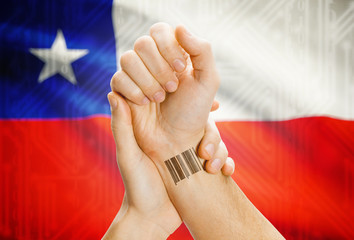 Barcode ID number on wrist and national flag on background - Chile