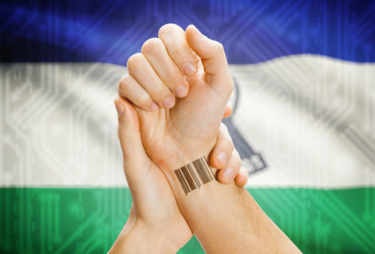 Barcode ID number on wrist and national flag on background - Lesotho