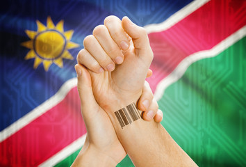 Barcode ID number on wrist and national flag on background - Namibia