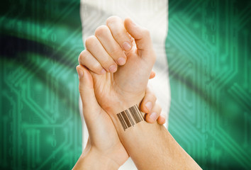 Barcode ID number on wrist and national flag on background - Nigeria