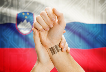 Barcode ID number on wrist and national flag on background - Slovenia