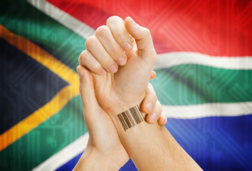 Barcode ID number on wrist and national flag on background - South Africa