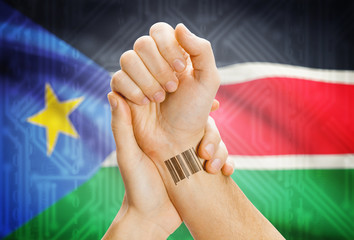 Barcode ID number on wrist and national flag on background - South Sudan
