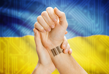 Barcode ID number on wrist and national flag on background - Ukraine