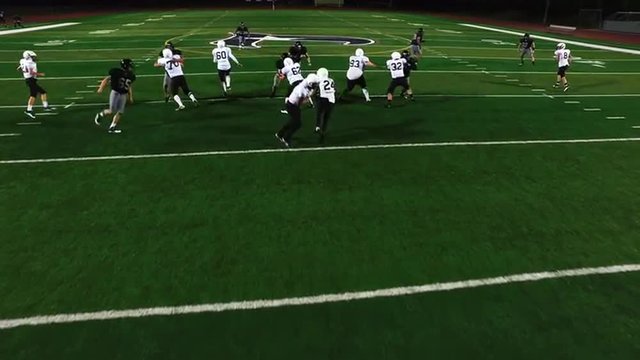 The camera pans overhead as a football player avoids being tackled and makes a touchdown
