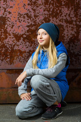 Hipster girl sitting on floor against red rusty wall