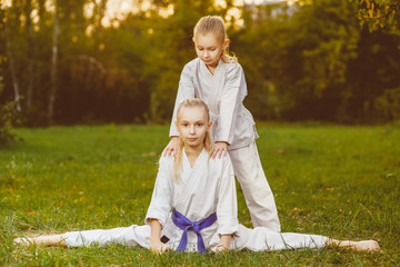 girls in white kimono during training karate exercises at summer outdoors
