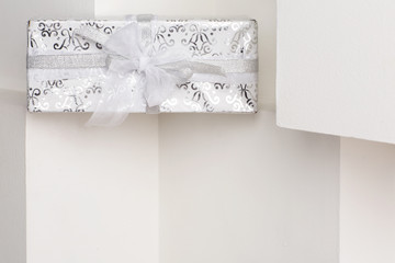 Gift box standing on a white shelf.