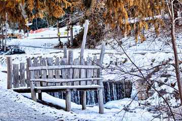 Uneven boards pier on mountain stream in the middle of snow, roc