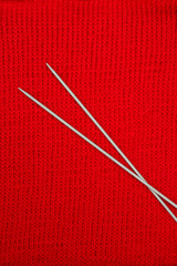 Knitting needles on knitted background