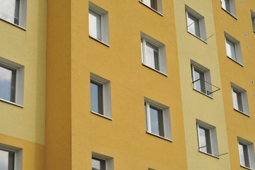 Fototapeta premium Pattern of apartment building windows on yellow wall.