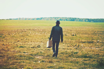 man going with suitcase in field. Concept freedom, loneliness 