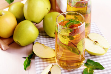 Glasses of apple juice with fruits and fresh mint on table close up