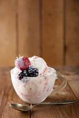 Delicious ice cream with fresh frozen berries, on rustic wooden background