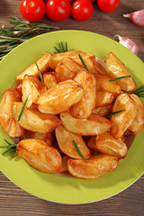 Baked potato wedges on wooden table, top view