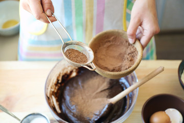 Woman preparing dough for chocolate pie on table close up