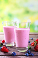 Glasses of berry smoothie on wooden table on blurred background