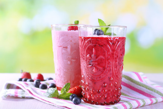 Glasses of berry smoothie on wooden table on blurred background