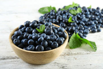 Tasty ripe blueberries with mint in bowl on table close up