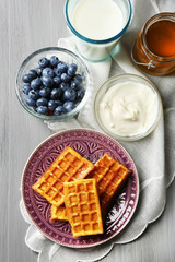 Sweet homemade waffles on plate, on color wooden background