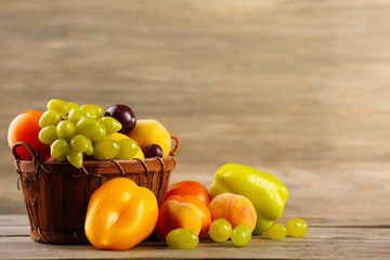 Heap of fresh fruits and vegetables in basket on wooden table close up
