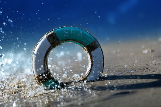 Beautiful life buoy in the sand on unfocused sea background