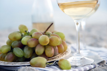 Romantic composition of white wine and grape on sandy beach