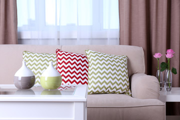 Fototapeta na wymiar Beige sofa with beautiful pillows and decorative vases on the table in front of it in the room