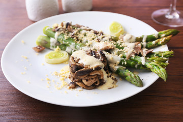 Delicious dish with asparagus and mushrooms on served wooden table in the restaurant, close up