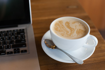 Hot art Latte Coffee in a cup and laptop on wooden table in Coff
