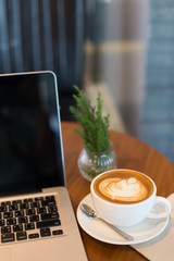 Hot art Latte Coffee in a cup and laptop on wooden table in Coff