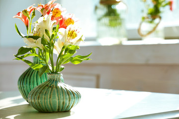 Beautiful Alstroemeria flowers in aquamarine vases on window background