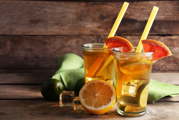 Iced tea with lemon and grapefruit on wooden background