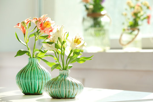 Beautiful Alstroemeria flowers in aquamarine vases on window background