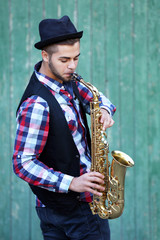 Fototapeta na wymiar The musician plays saxophone on green wooden background