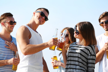 Young people with beer on the riverside