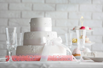 Wedding layered cake in decorated restaurant on white wall background