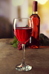 Red wine glass  with bottle on wooden table against unfocused background
