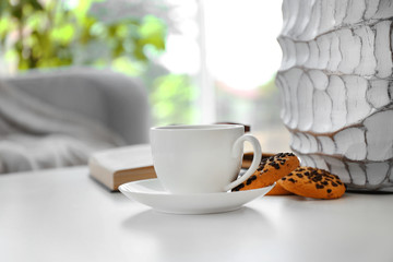 Cup of coffee with biscuits on table in room
